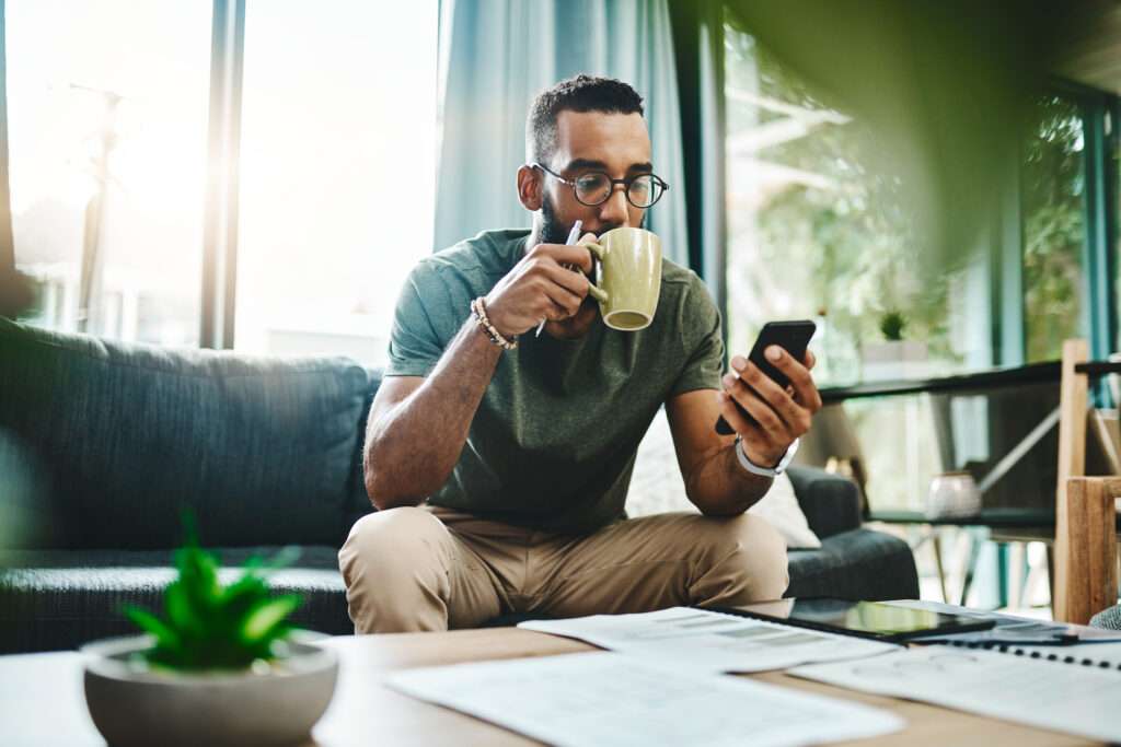 man engaged in healthcare self scheduling on smart phone drinking coffee