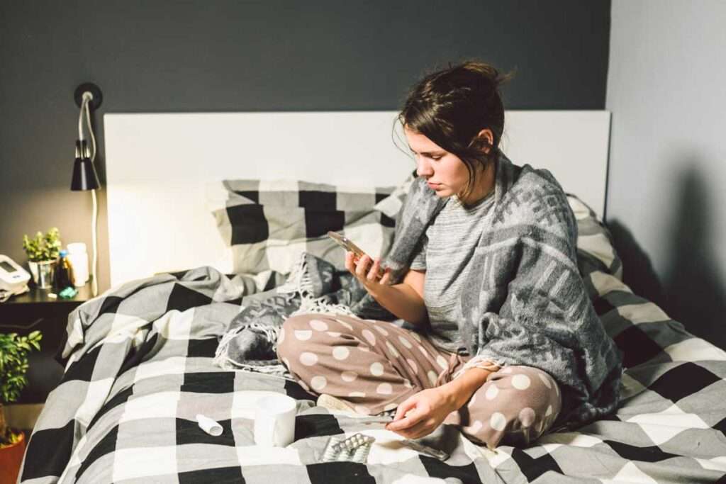 woman sitting on bed using Patient Registration Solution on cell phone