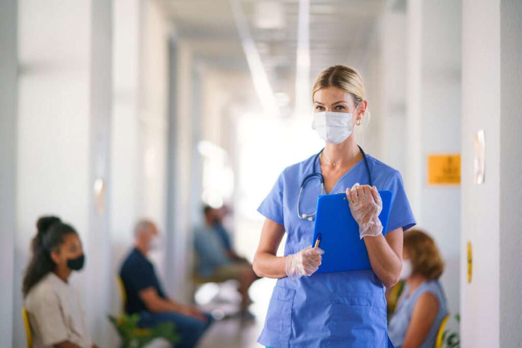 Masked female healthcare worker holding patient chart