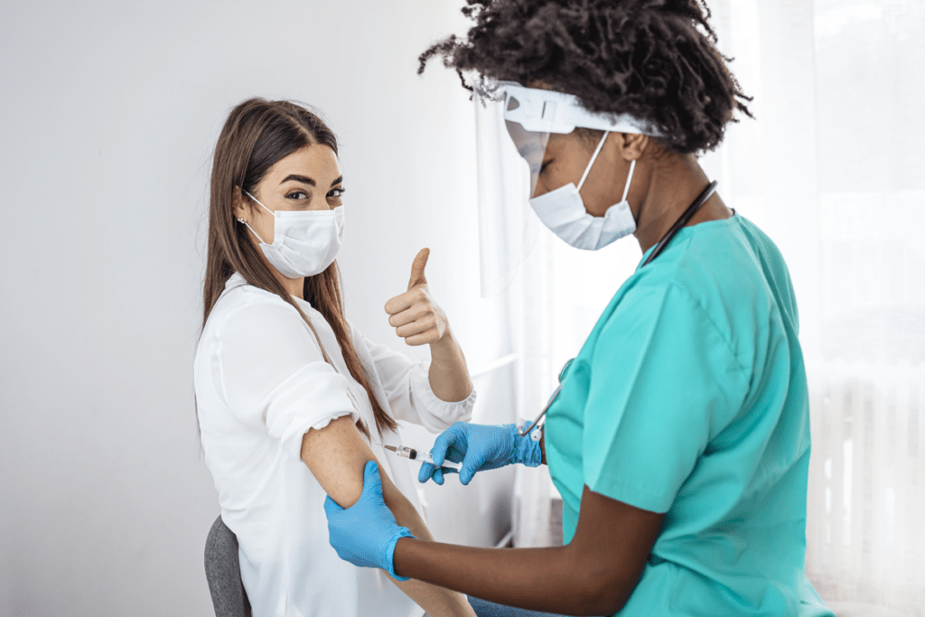 Patient receiving vaccine giving thumbs up after scheduling appointment online with Dash Schedule