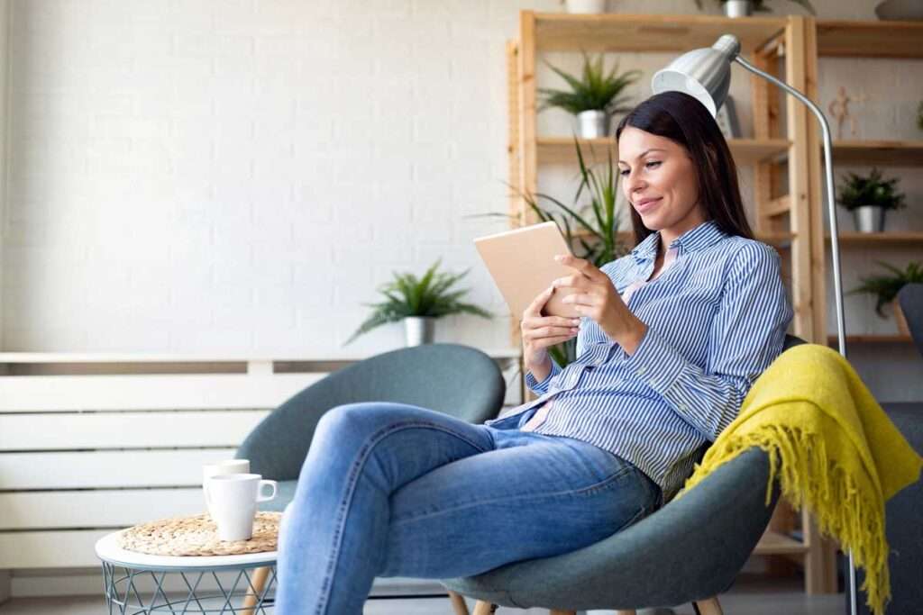 woman sitting in chair using tablet for online booking for doctors