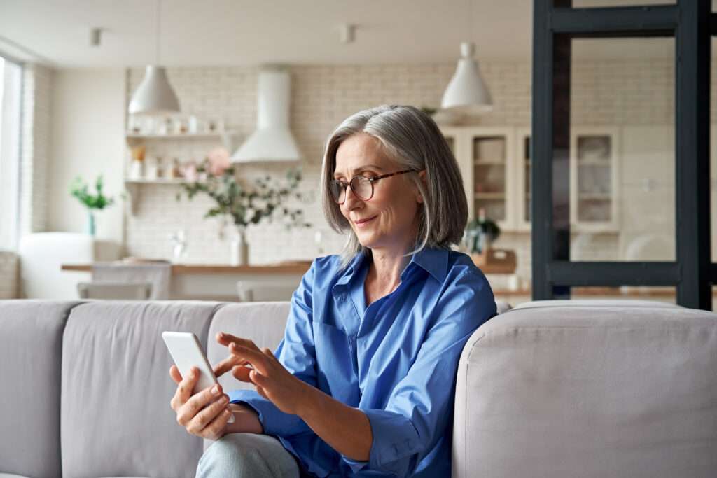 Mature woman using smartphone to access patient appointment reminder software
