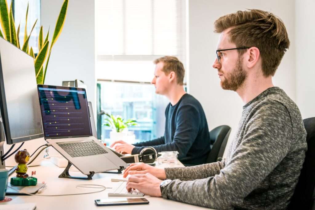 men in front of computer screens managing patient scheduling