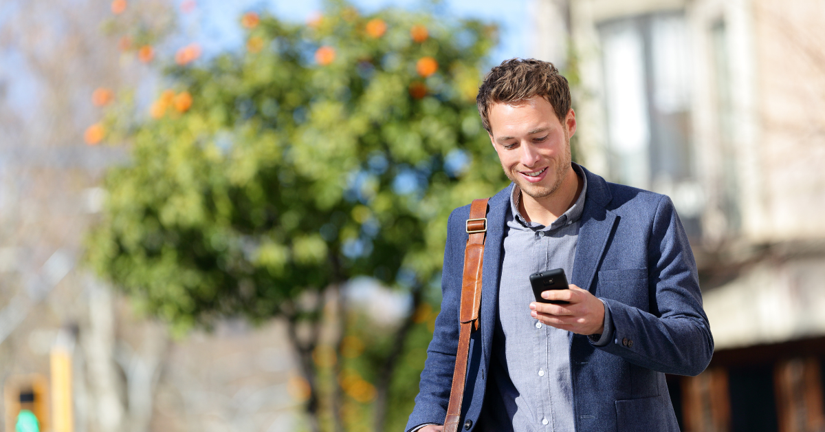 Young man holding mobile phone while using Relatient's patient self-scheduling software